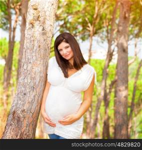 Portrait of expectant arabic female outdoors, spending time in garden in summer time, touching belly, happy and healthy pregnancy, love concept