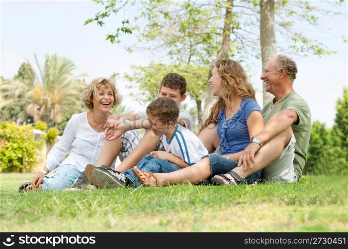 Portrait of extended family relaxing on sunny day in park and having good time