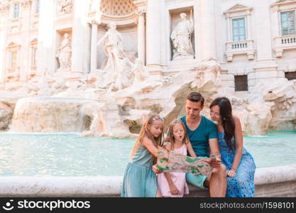 Portrait of family at Fontana di Trevi, Rome, Italy. Happy parents and kids enjoy italian vacation holiday in Europe.. Happy family near Fontana di Trevi with city map