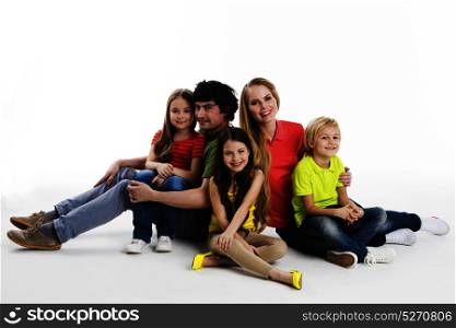 Portrait of family at studio. Portrait of happy family with three children sitting on the floor at studio isolated on white background