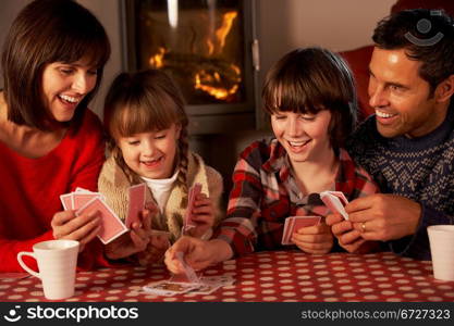 Portrait Of Family Playing Cards By Cosy Log Fire