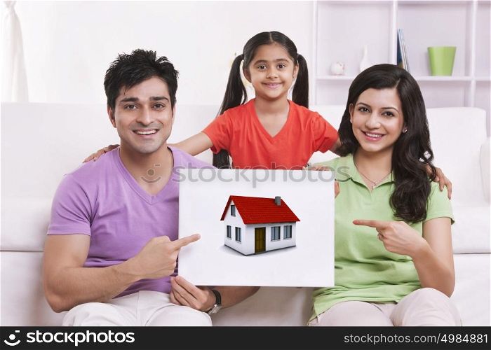 Portrait of family pointing to picture of house