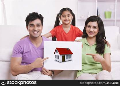 Portrait of family pointing to picture of house