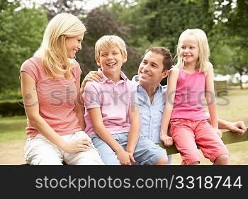 Portrait Of Family Sitting On Fence In Countryside