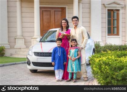 Portrait of family standing next to new car