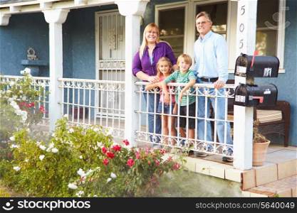 Portrait Of Family Standing On Porch Of Suburban Home