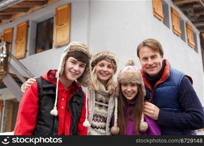 Portrait Of Family Standing Outside Chalet On Ski Holiday