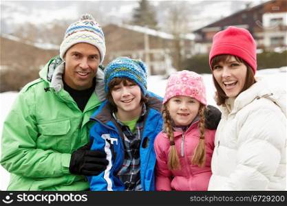 Portrait Of Family Wearing Winter Clothes In Snowy Landscape