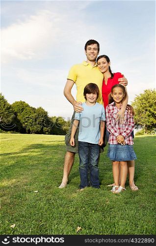 Portrait of family with two children standing on grass