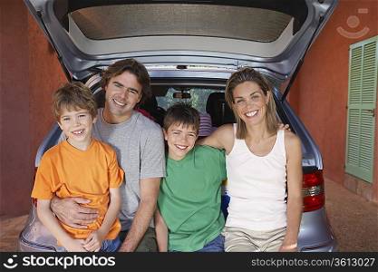 Portrait of family with two sons (6-11) sitting on car tailgate