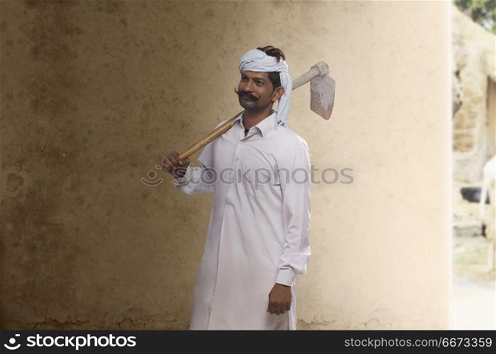 Portrait of farmer carrying hoe on his shoulder