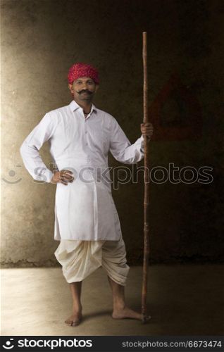 Portrait of farmer in traditional clothing holding stick