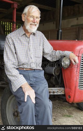 Portrait Of Farmer Sitting Next To Vintage Farm Tractor