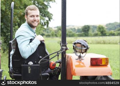 Portrait Of Farmer Sitting On Tractor In Field