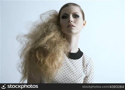 portrait of fashion blonde girl with creative modern hairdo, strong make-up and pois shirt