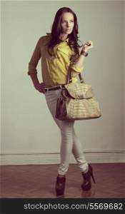 portrait of fashion brunette with modern casual style and natural hair-style. Wearing yellow shirt, white pants and taking cool bag in the hand