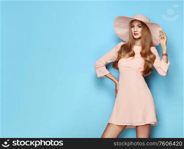 Portrait of Fashion Young woman in Pink Dress. Lady in Stylish Summer Outfit. Girl Posing on a Blue Background. Stylish Hairstyle. Spring collection casual clothes