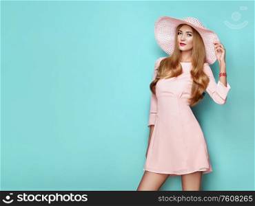 Portrait of Fashion Young woman in Pink Dress. Lady in Stylish Summer Outfit. Girl Posing on a turquoise Background. Stylish Hairstyle. Spring collection casual clothes
