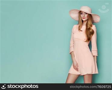 Portrait of Fashion Young woman in Pink Dress. Lady in Stylish Summer Outfit. Girl Posing on a turquoise Background. Stylish Hairstyle. Spring collection casual clothes