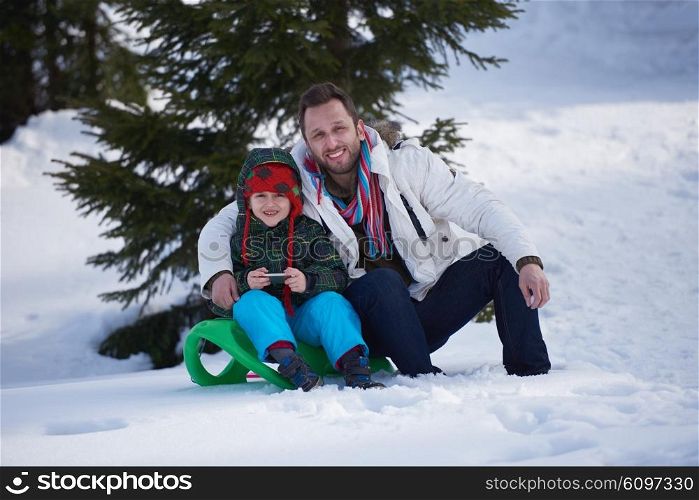 portrait of father and son on snow sitting on sled at beautiful sunny winter day