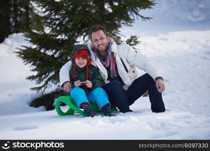 portrait of father and son on snow sitting on sled at beautiful sunny winter day