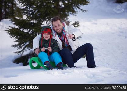 portrait of father and son on snow sitting on sled at beautiful sunny winter day