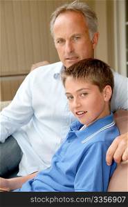Portrait of father and son sitting in sofa