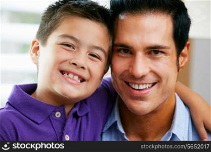 Portrait Of Father And Son Sitting On Sofa At Home