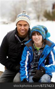 Portrait Of Father And Son Wearing Winter Clothes In Snowy Landscape