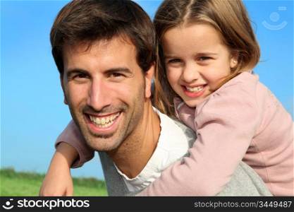 Portrait of father giving piggyback ride to daughter