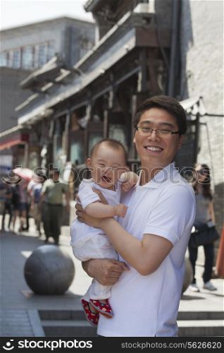 Portrait of father holding his baby son, outdoors Beijing