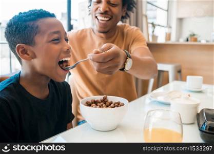 Portrait of father spending time with son while having breakfast together at home. Family and lifestyle concept.