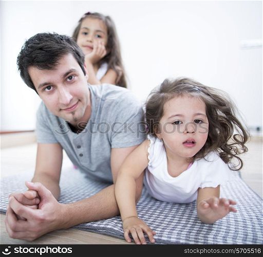 Portrait of father with daughters lying on blanket at home