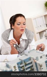 Portrait of female architect with architectural model in modern office