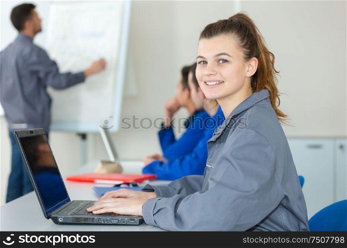 portrait of female blue-collar aprpentice using laptop in classroom