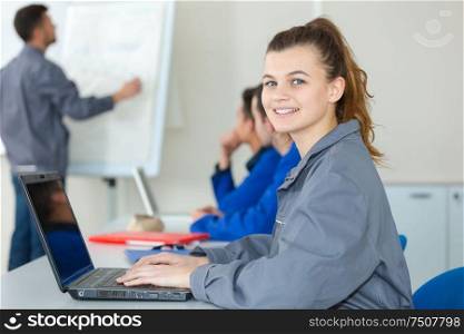 portrait of female blue-collar aprpentice using laptop in classroom