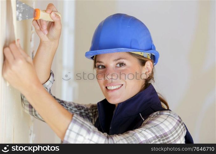 portrait of female builder stripping wallpaper
