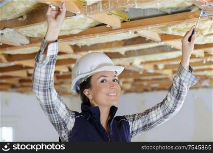portrait of female builder using screwdriver on wooden beam