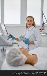 Portrait of female cosmetologist working with laser machine in modern medical office. Professional cosmetology concept. Portrait of female cosmetologist working with laser machine