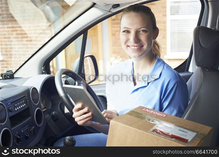 Portrait Of Female Courier In Van With Digital Tablet Delivering Package To Domestic House