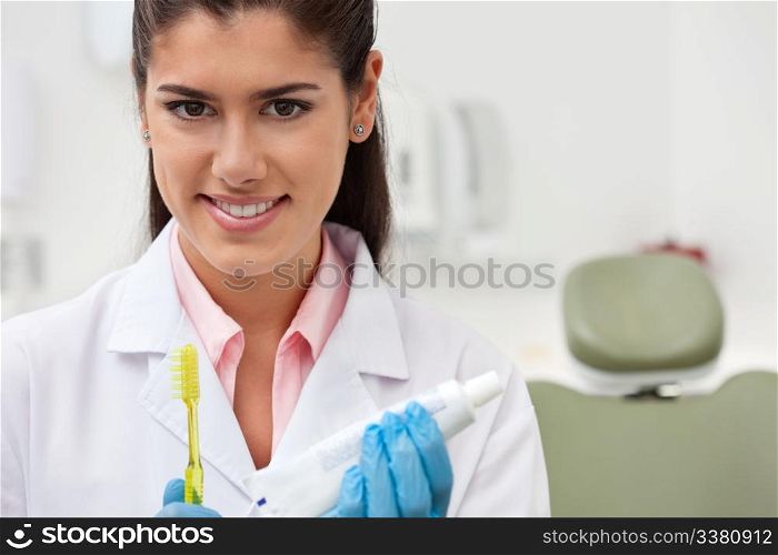 Portrait of female dentist holding toothbrush and toothpaste