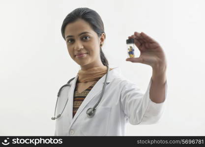 Portrait of female doctor holding pill bottle isolated over white background