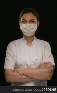 Portrait of female doctor in mask over black background