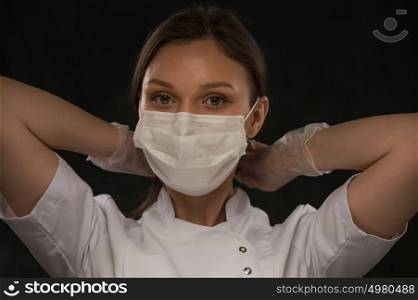 Portrait of female doctor putting on mask over black background