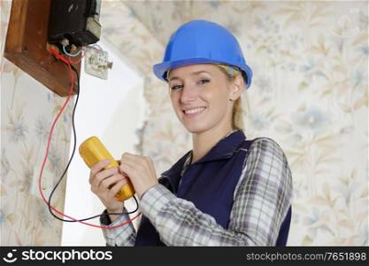 portrait of female electrician using multimeter