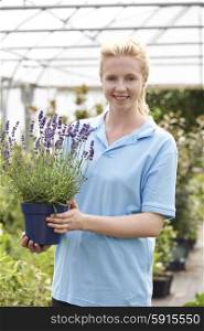 Portrait Of Female Employee At Garden Center Holding Plant