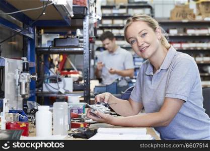 Portrait Of Female Engineer In Factory Measuring Component At Work Bench Using Micrometer