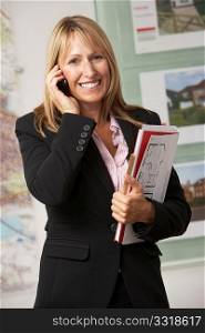 Portrait Of Female Estate Agent In Office On Phone