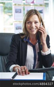 Portrait Of Female Estate Agent On Phone In Office