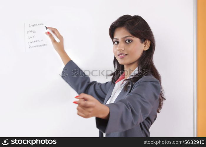 Portrait of female executive writing on white board